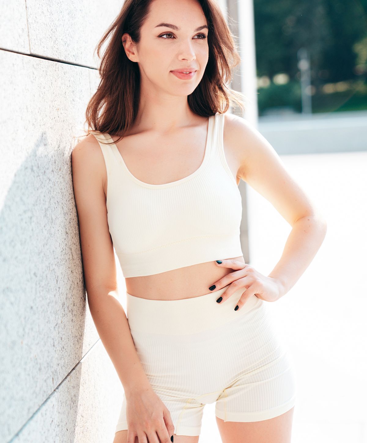 Woman posing in beige activewear against a wall.
