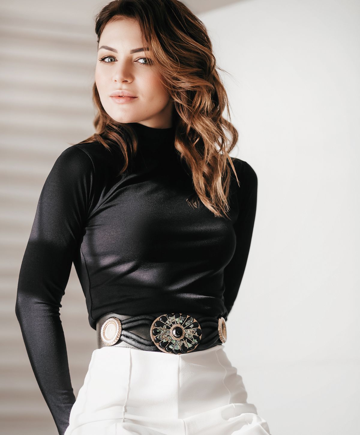 Woman in stylish black top and white pants.