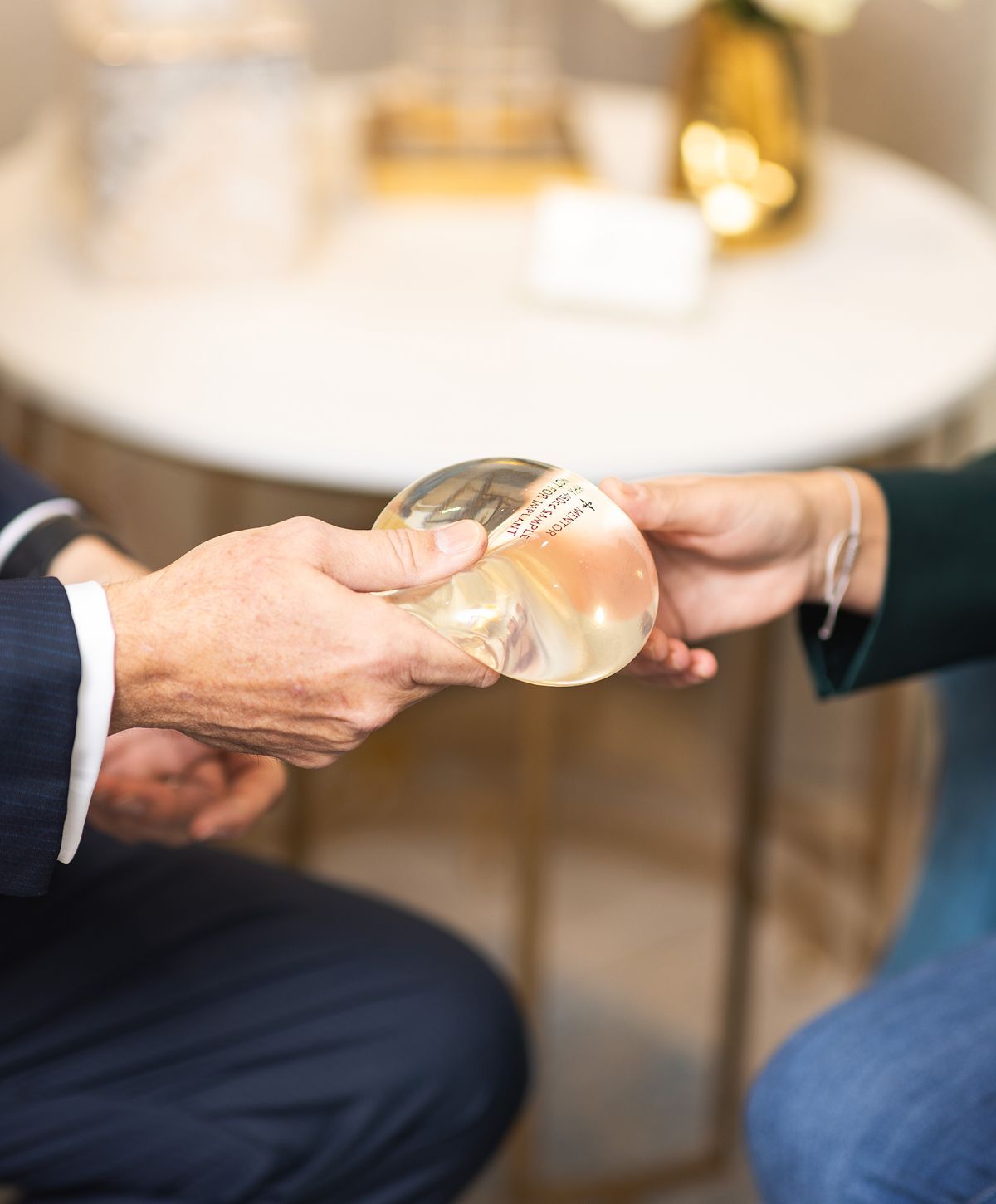Hands exchanging a clear medical implant.