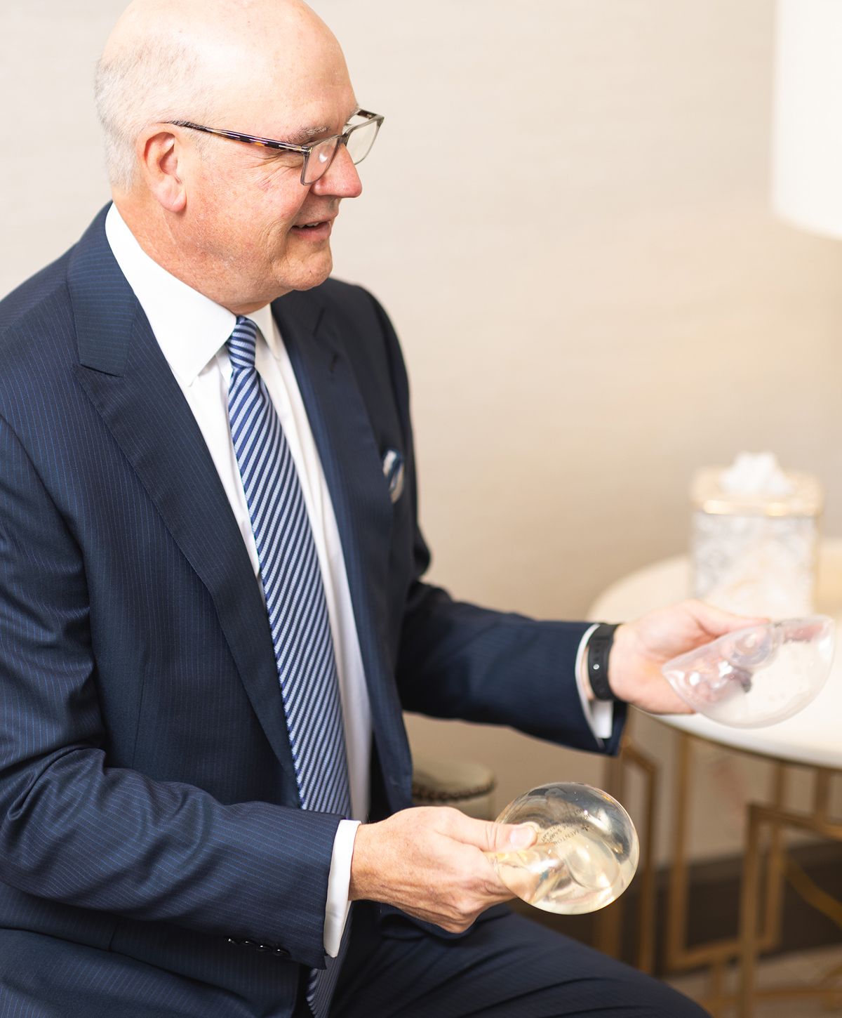 Man holding silicone breast implant models.