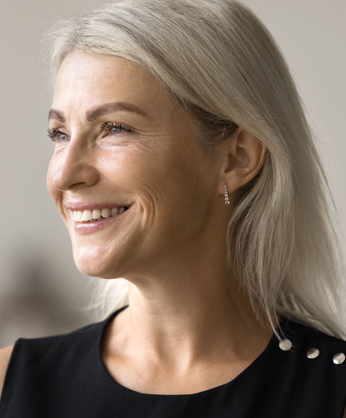 Smiling woman with long silver hair and earrings.