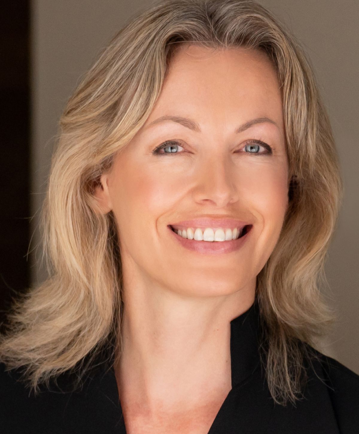 Smiling woman with blonde hair and light background.