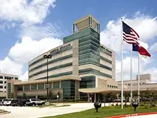 Modern hospital building with flags in foreground.
