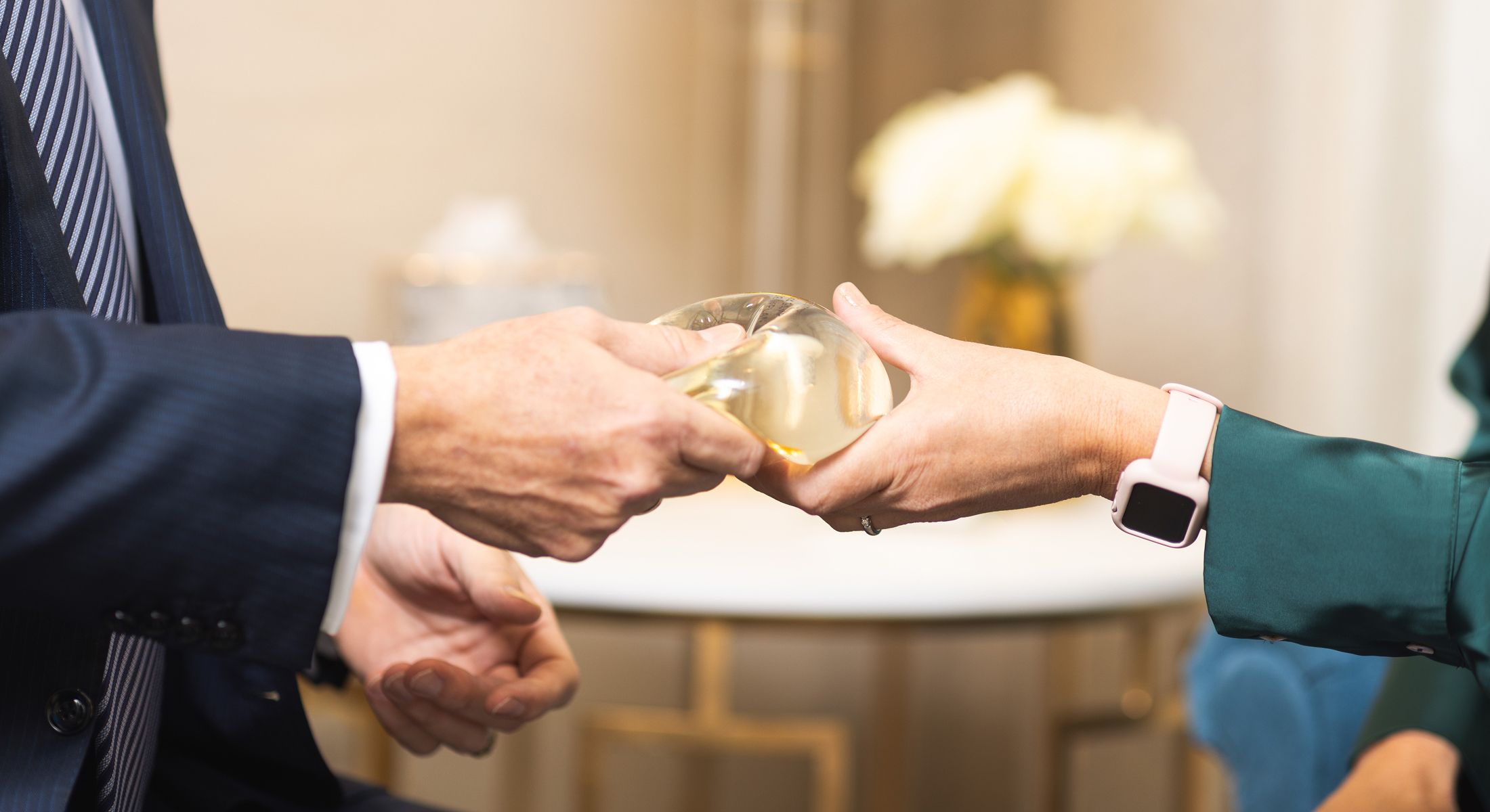 Hands exchanging a round, transparent object.
